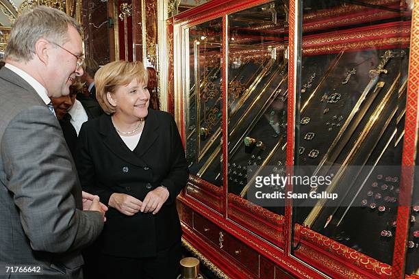 German Chancellor Angela Merkel smiles while looking at jewelry in an exhibit at the Gruenes Gewoelbe Museum, while museum director Dirk Syndram...