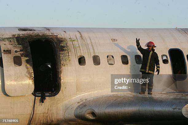 An Iranian firefighter talks to comrades as he stands amid the wreckage of an Iranian airliner which caught fire on landing at the Hasheminejad...