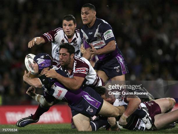 Nathan Friend of the Storm passes the ball whilst being tackled during the round 26 NRL match between the Melbourne Storm and the Manly Warringah Sea...