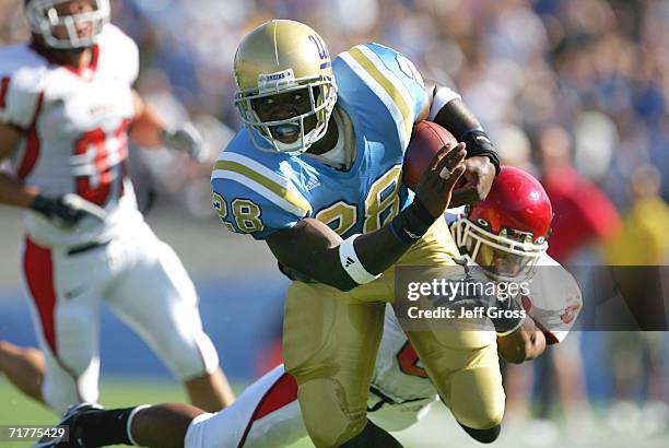 Chris Markey of the UCLA Bruins carries the ball under pressure from Eric Shyne of the Utah Utes during the college football game held on Septemeber...