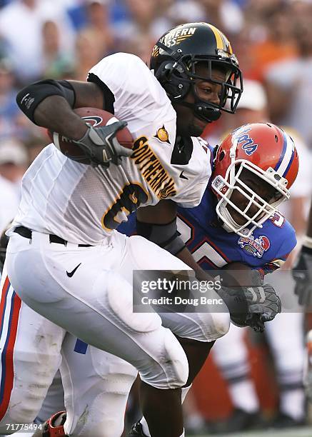 Running back Larry Thomas of the Southern Miss Golden Eagles is brought down by defensive end Ray McDonald of the University of Florida Gators at Ben...