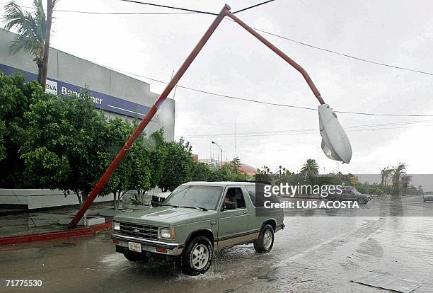 Un vehiculo pasa debajo de un poste de luz a punto de caer luego del paso del Huracan John en La Paz, Baja California, el 2 de setiembre de 2006....