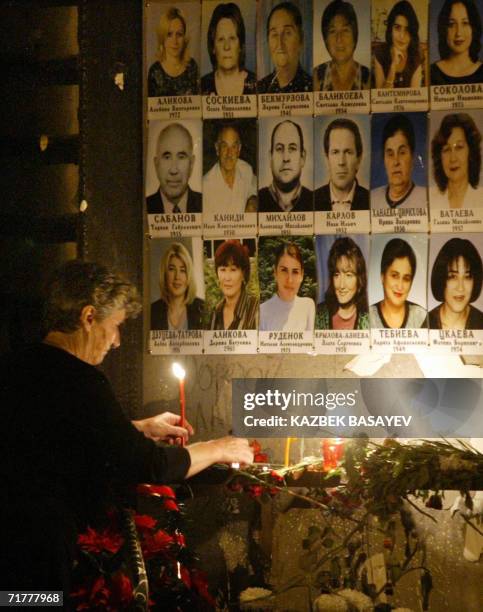 Beslan, RUSSIAN FEDERATION: A woman lights a candle at a wall of the destroyed school gymnasium decorated with pictures of the victims during a...