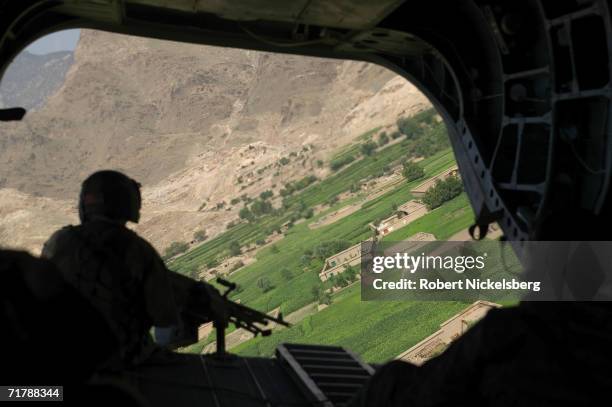 Army flight engineer mans a machine gun as a Chinook CH-47 helicopter lands on a resupply flight for the 10th Mountain Division's Forward Operating...