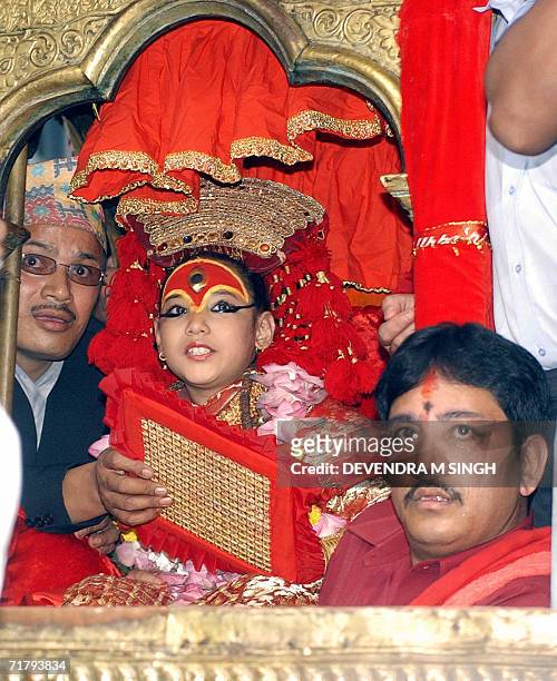 Kumari, a pre-pubescent girl revered by many in Nepal as a living goddess, is flanked by Buddhist priests during a chariot procession, during the...