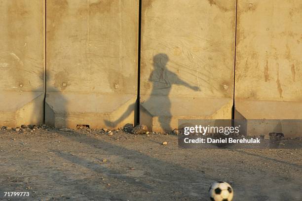 Young Iraqi boys play soccer amongst protective blast walls on September 6, 2006 in Baghdad, Iraq. It was here on October 14, 2005 two suicide...