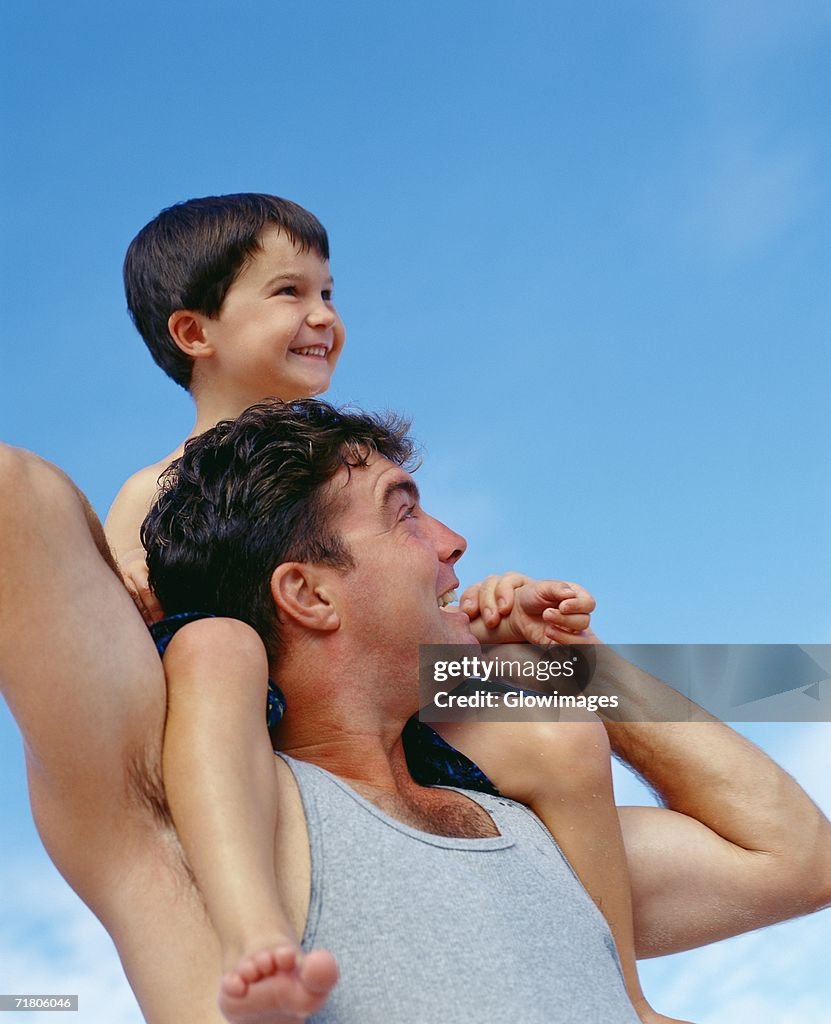 Low angle view of a mid adult man carrying his son on his shoulders, Bermuda