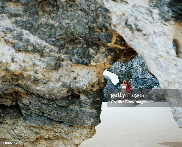 couple sitting on rocks, bermuda - bermuda beach stockfoto's en -beelden