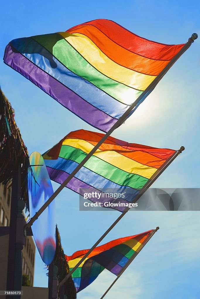 Low angle view of three gay pride flags fluttering on a building