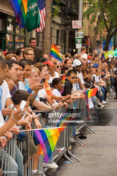 large group of people holding gay pride flags and standing by a railing - pride march stock pictures, royalty-free photos & images