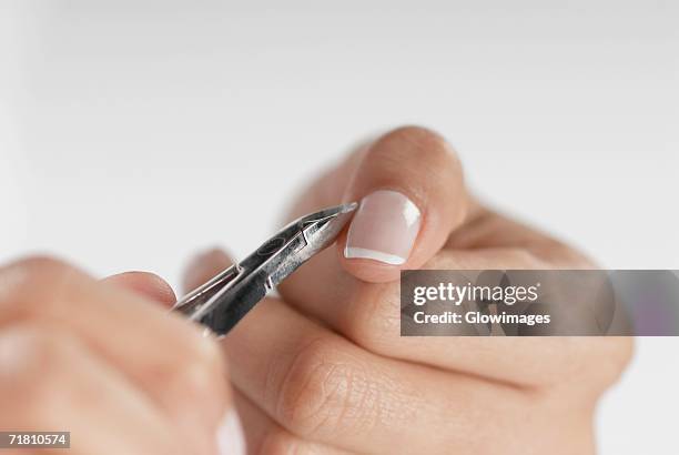 close-up of a woman's hand using a nail scissor - nail scissors - fotografias e filmes do acervo