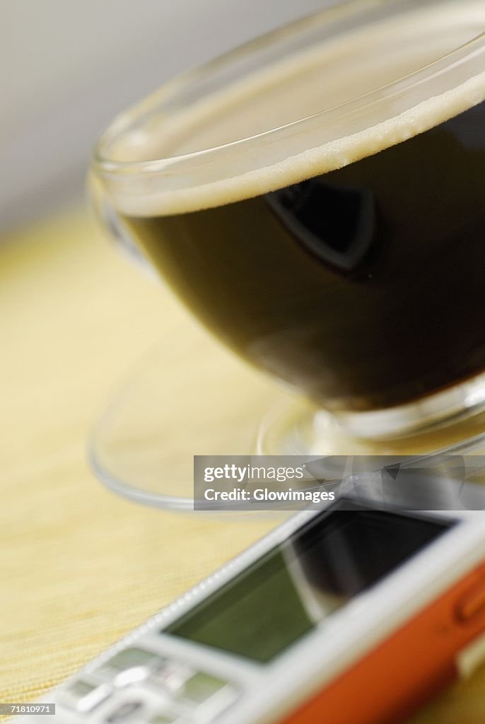 Close-up of a cup of black coffee and a mobile phone