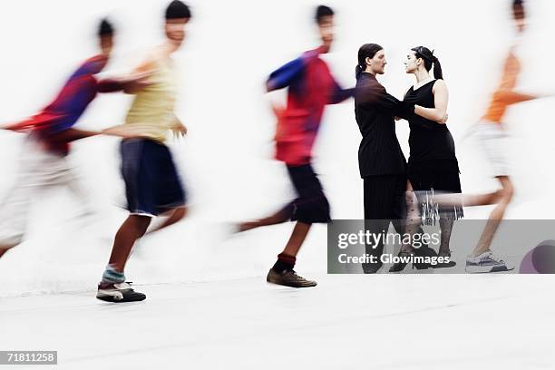 side profile of a young couple tangoing with four boys running in front of them - tangoing stock pictures, royalty-free photos & images