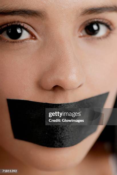 portrait of a young woman with adhesive tape over her mouth - gagged woman stock-fotos und bilder
