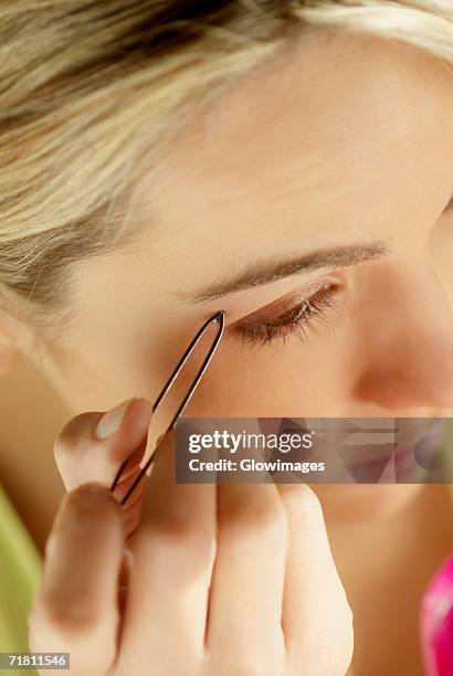 close-up of a young woman tweezing her eyebrows - eyebrow tweezers imagens e fotografias de stock