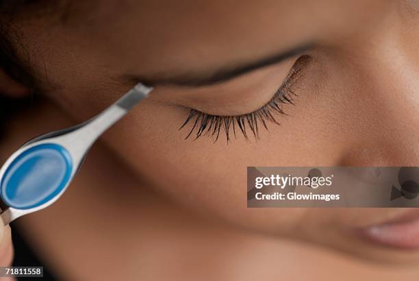 close-up of a young woman plucking her eyebrows - eyebrow tweezers imagens e fotografias de stock