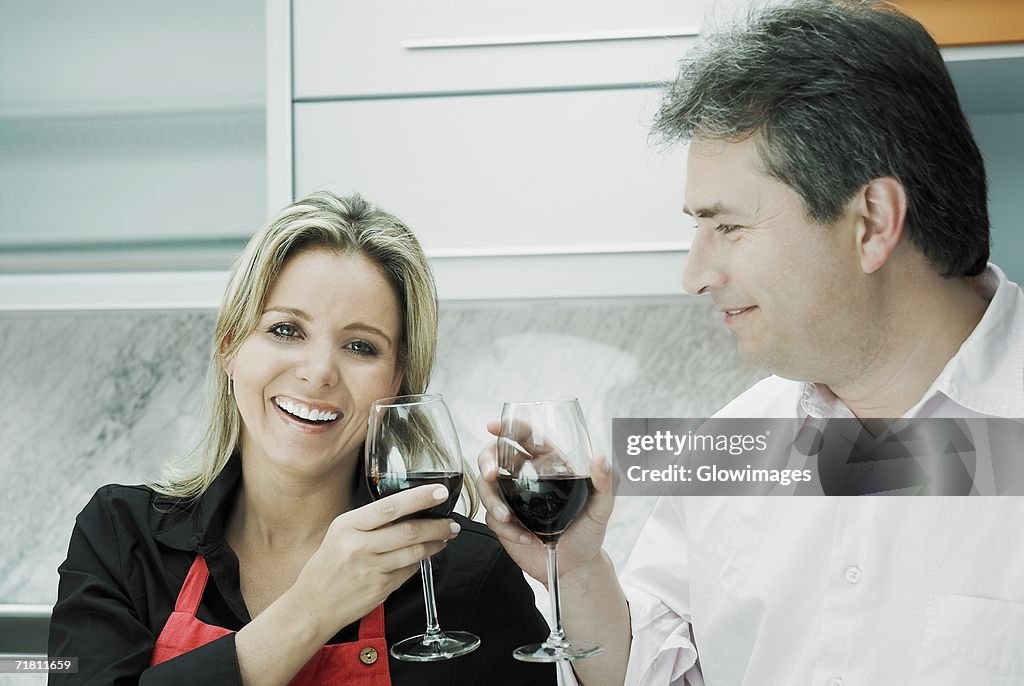 Close-up of a mid adult woman and a mature man toasting glasses of wine and smiling