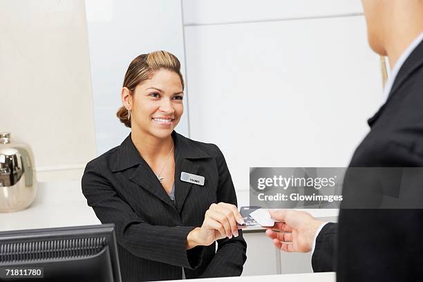 customer giving a credit card to a female receptionist - metallic suit stock pictures, royalty-free photos & images
