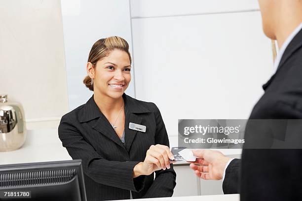 customer giving a credit card to a female receptionist - metallic suit - fotografias e filmes do acervo