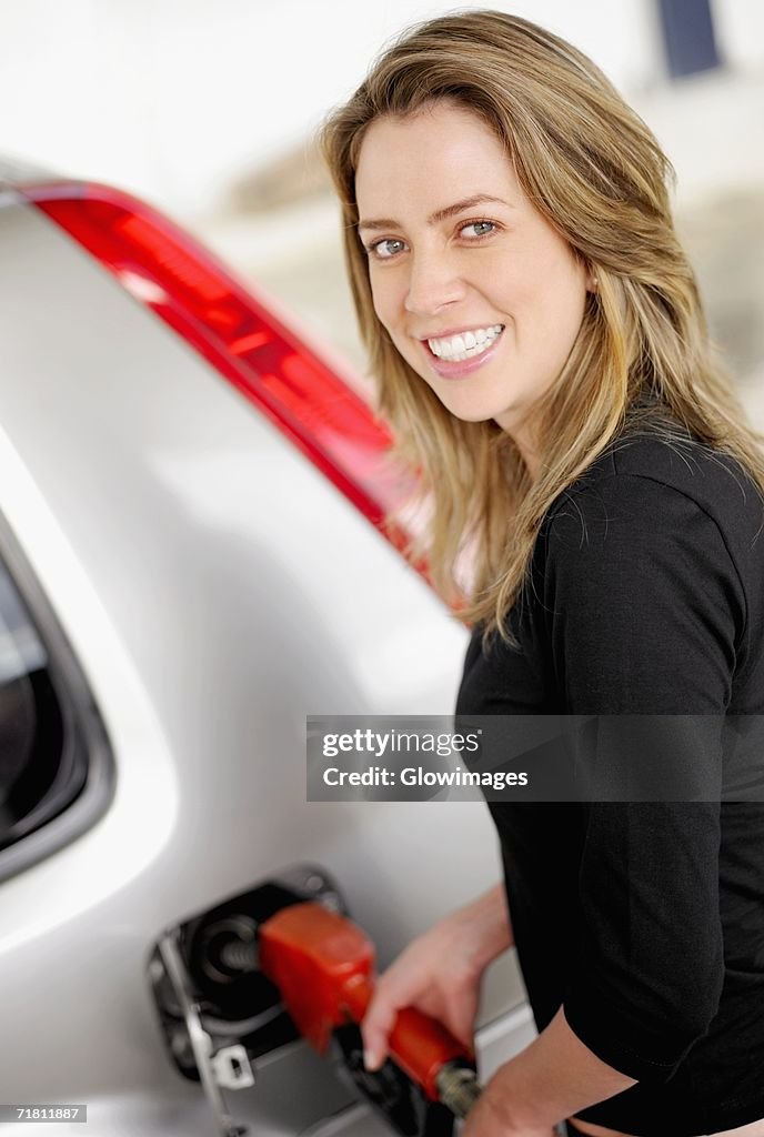 Portrait of a young woman refueling a car