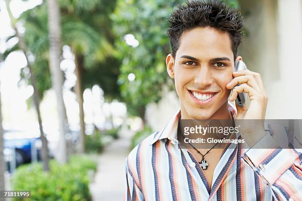 portrait of a young man talking on a mobile phone - cross stripes shirt stockfoto's en -beelden