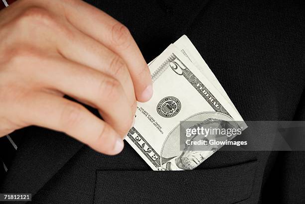 mid section view of a businessman putting dollar bills in his pocket - five dollar bill stock pictures, royalty-free photos & images
