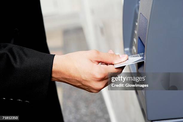 close-up of a person's hand inserting a credit card into an atm - inserts stock pictures, royalty-free photos & images