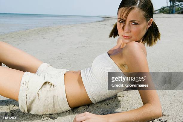 portrait of a young woman reclining on the beach - scheitel stock-fotos und bilder