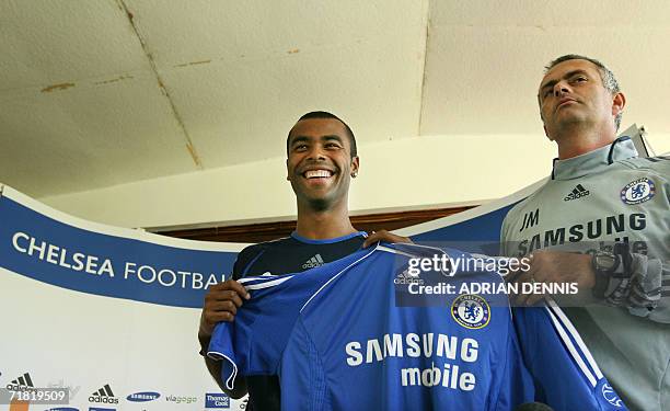 Cobham, UNITED KINGDOM: Chelsea's latest football signing Ashley Cole poses with his new shirt alongside Club manager Jose Mourinho during a press...