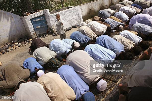 Afghan refugees kneel during prayers on September 8, 2006 at the Khazana camp on the outskirts of Peshawar, Pakistan. While some of the refugees have...