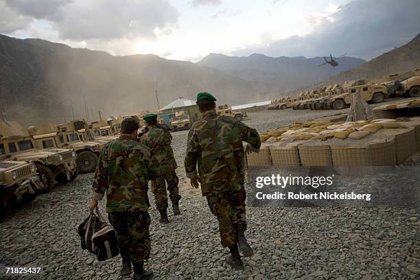 Afghan National Army soldiers walk through the motor pool, as a US Army helicopter departs from the Forward Operation Base in September 1 in Naray,...