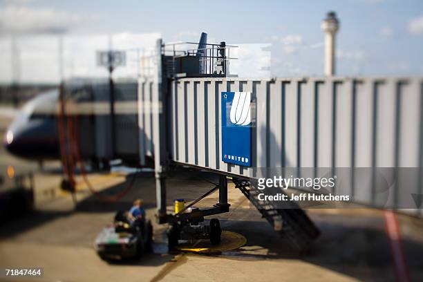 Grounds crew do last minute work as the gangway is extended to an outbound United Airlines flight at Chicago?s O?Hare airport as airline passengers...