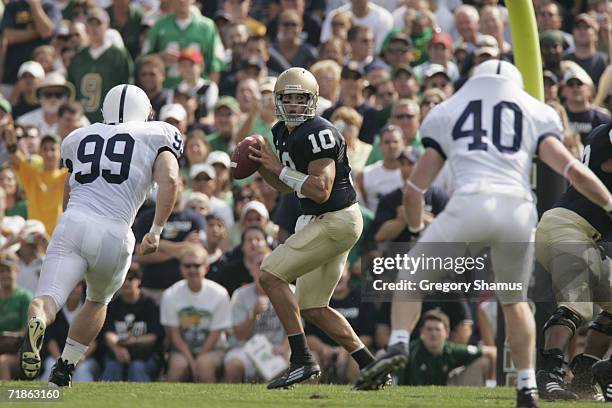 Quarterback Brady Quinn of the Notre Dame Fighting Irish looks to pass while being defended by Jim Shaw and Dan Connor of the Penn State Nittany...