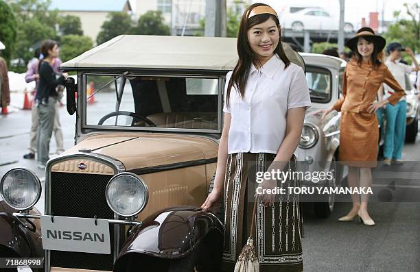 Models stand beside vintage cars of Japan's auto giant Nissan Motor at its Engine Museum in Yokohama, suburban Tokyo, 13 September 2006 during a...