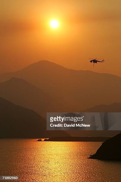 Firefighting helicopter flies through smoke that envelops Pyramid Lake as the 27,000-acre Day Fire, so-named because it has been burning since Labor...