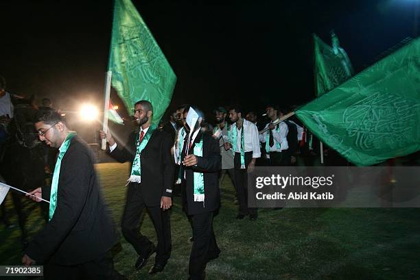 Palestinian grooms hold Hamas flags and wear Hamas insignia green scarves as they line up for a mass wedding party organized by the ruling Islamist...