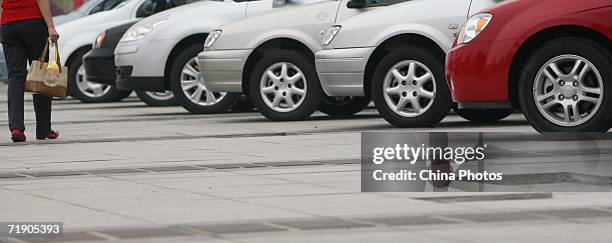 Woman walks past cars on sale during an auto exhibition at the Chongqing Auto Expo Center September 16, 2006 in Chongqing Municipality, China....