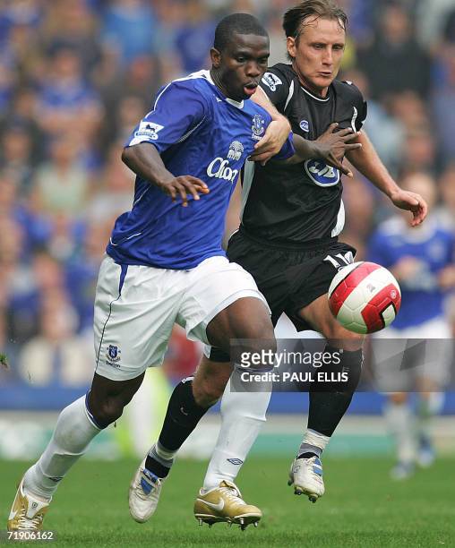 Liverpool, UNITED KINGDOM: Everton's Joseph Yobo is challenged by Wigan Athletic's Andreas Johasson during their English Premiership football match...