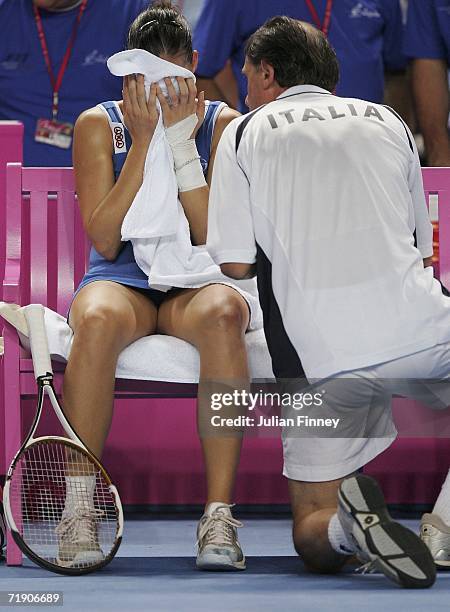 Flavia Pennetta of Italy holds her towel on her face as Coach, Corrado Barazzutti of Italy give advice in her match against Justine Henin-Hardenne of...