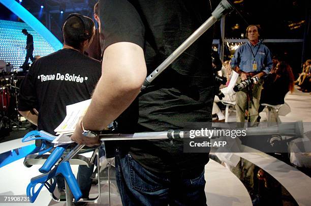 Un collaborateur de l'animateur de France 2 Michel Drucker porte ses bequilles, le 16 septembre 2006 avant le debut, en direct d'un studio monte...