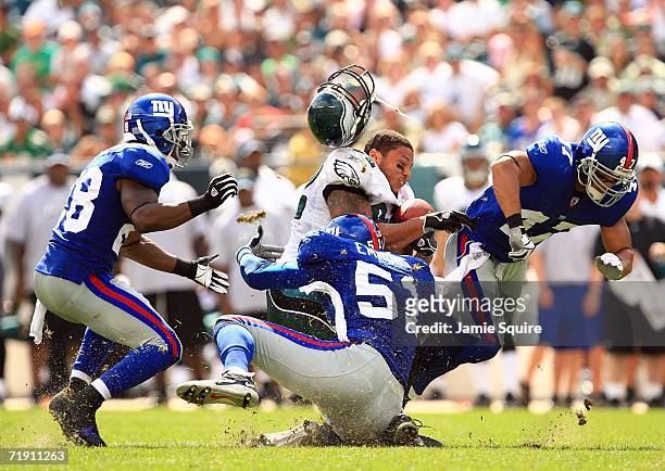 Smith of the Philadelphia Eagles loses his helmet as he is hit by Carlos Emmons, Gibril Wilson, and Will Demps of the New York Giants during the...
