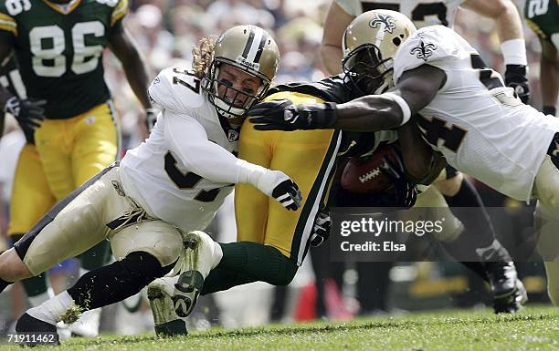 Charles Woodson of the Green Bay Packers is tackled by Steve Gleason and Danny Clark of the New Orleans Saints on September 17, 2006 at Lambeau Field...