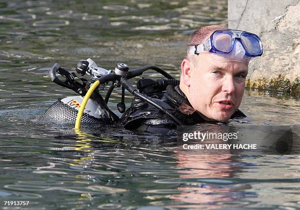 Monaco Prince Albert II poses after diving with a statue of a dolphin 17 September 2006 during the launching of Operation Mimo, celebrating the...