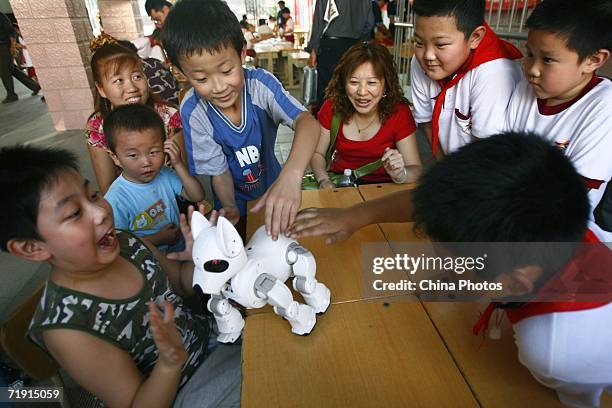 Students play with a robot dog at a science popularization activity on September 17, 2006 in Beijing, China. September 17 marks the National Science...