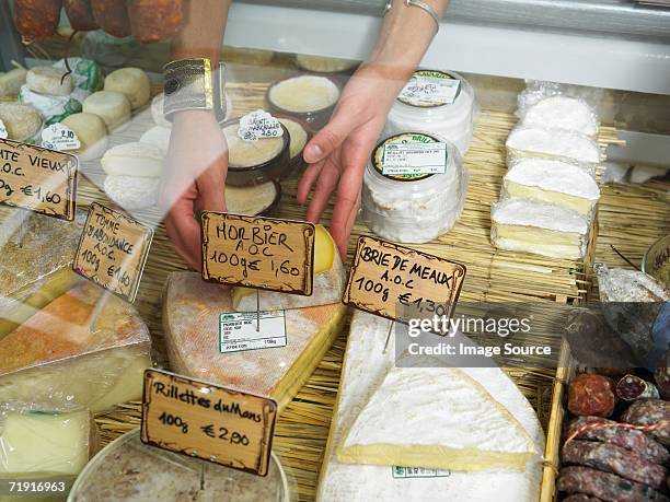 woman reaching into delicatessen display - camembert stock-fotos und bilder