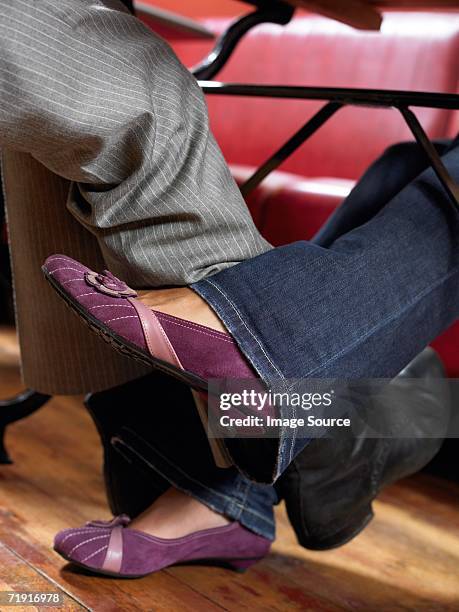 man and woman playing footsie under table - footsie under table stock-fotos und bilder