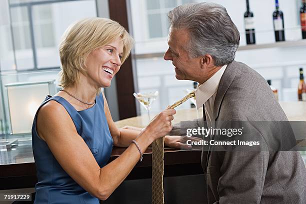 woman pulling man's tie - flirten stockfoto's en -beelden