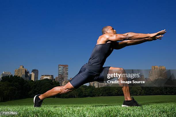 man stretching in central park - male knee stock pictures, royalty-free photos & images