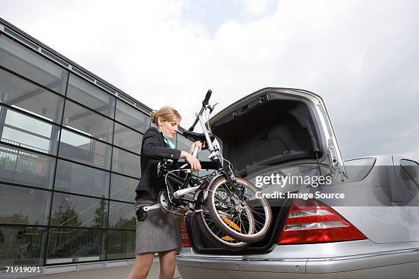 businesswoman putting folded bicycle in car boot - klapprad business stock-fotos und bilder