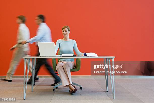 men walking past woman at desk - walking past office wall stock pictures, royalty-free photos & images